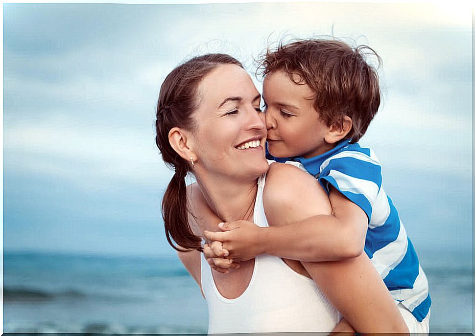 Mother spending time with her son on the beach, who kisses her.