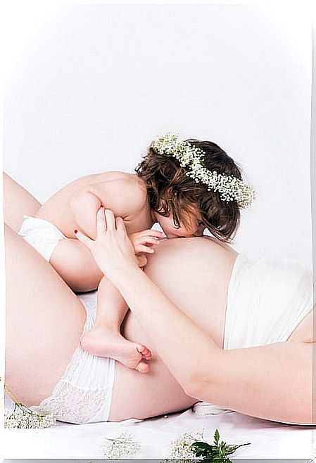 pregnant-lying-with-daughter-kissing-the-belly