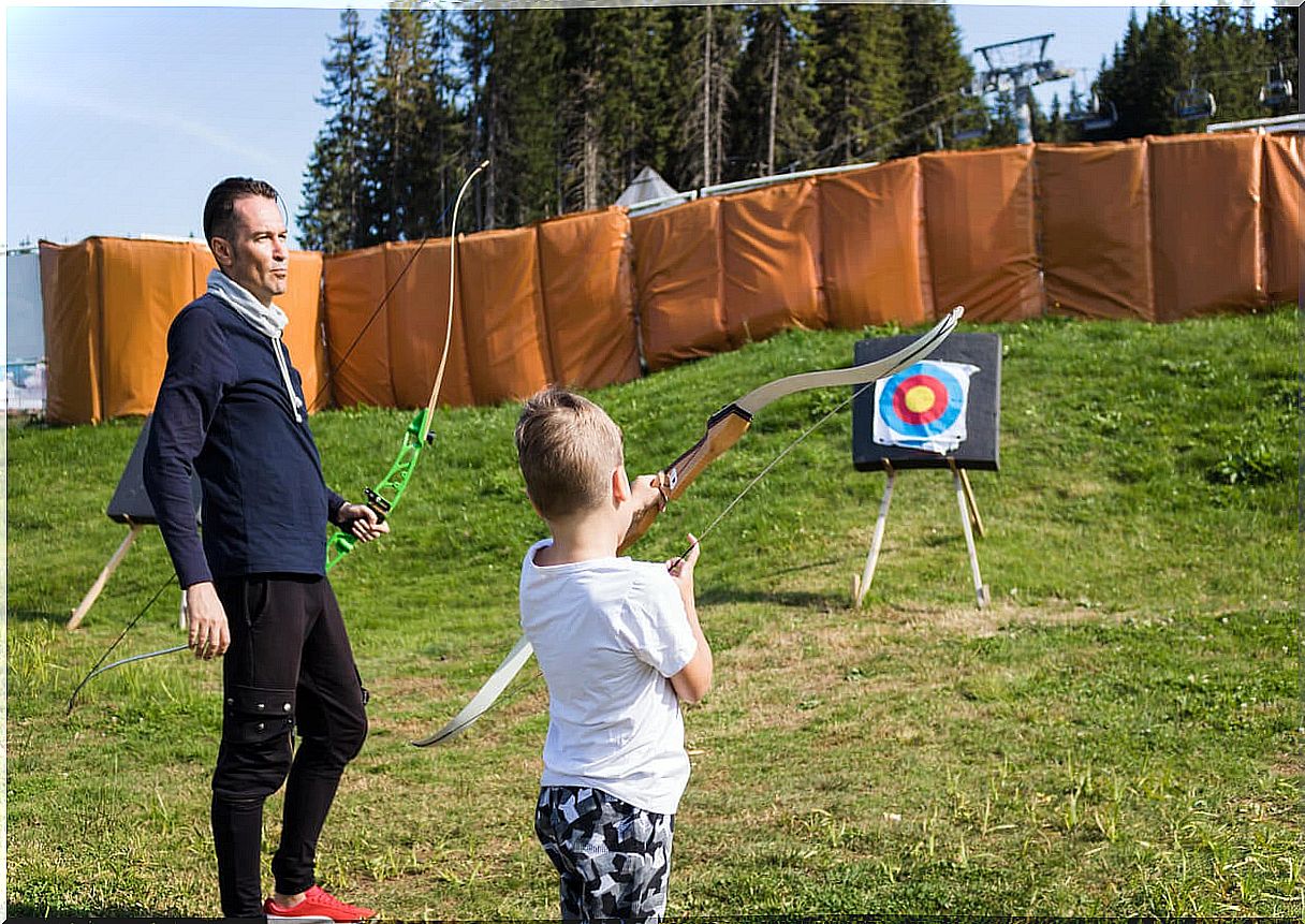 Boy practicing archery with his trainer.