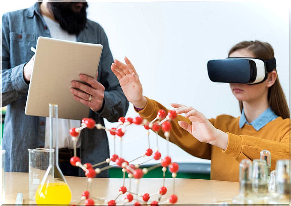 Little girl in the classroom using virtual and augmented reality with her teacher taking notes.