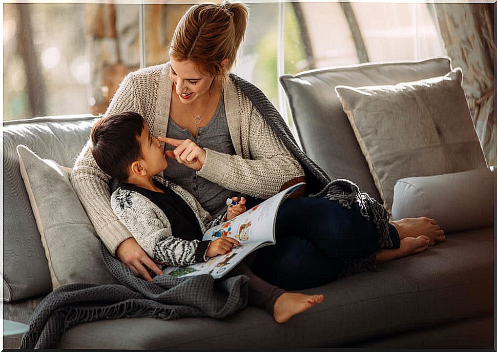 Mother and son reading a story on the couch during their quarantine to cope with boredom.