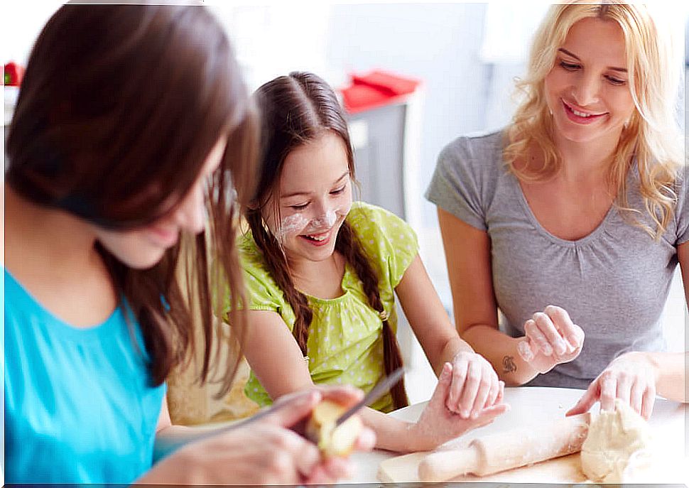 Teen girls making a pizza with their mother.