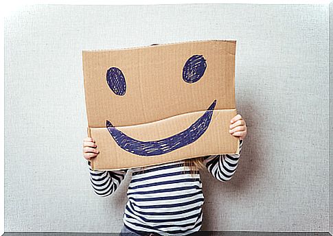 Boy holding a sign on which there is a smiling face