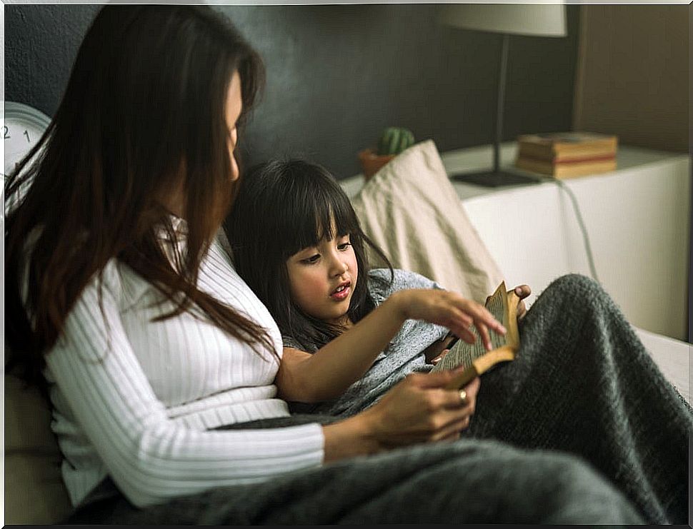 Mother reading to her daughter a book before sleeping.