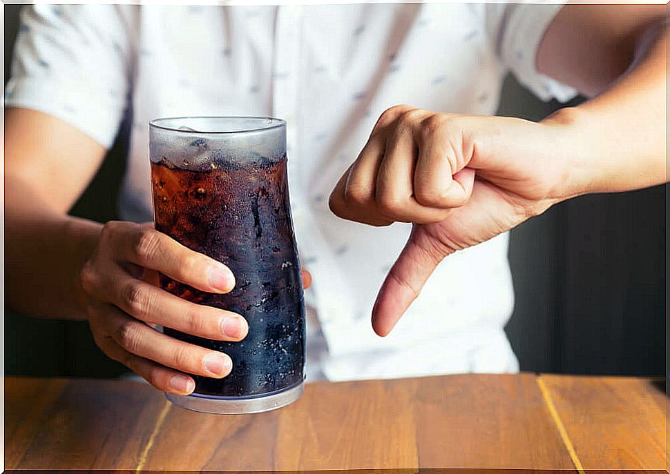 Boy with a soda in one hand and saying no with his thumb down.