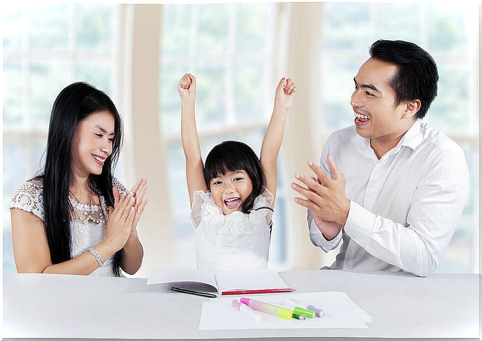 Parents congratulating their daughter for doing her homework well in a fun way.