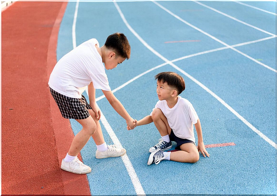 Child helping another on the running track thanks to healthy competitiveness.