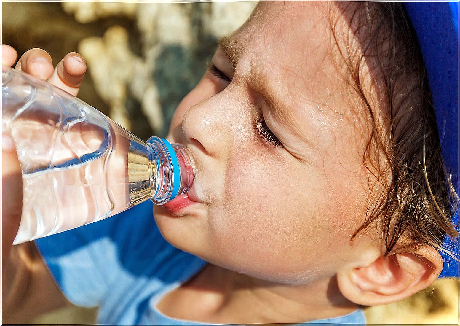 Child drinking water because he sweats a lot.