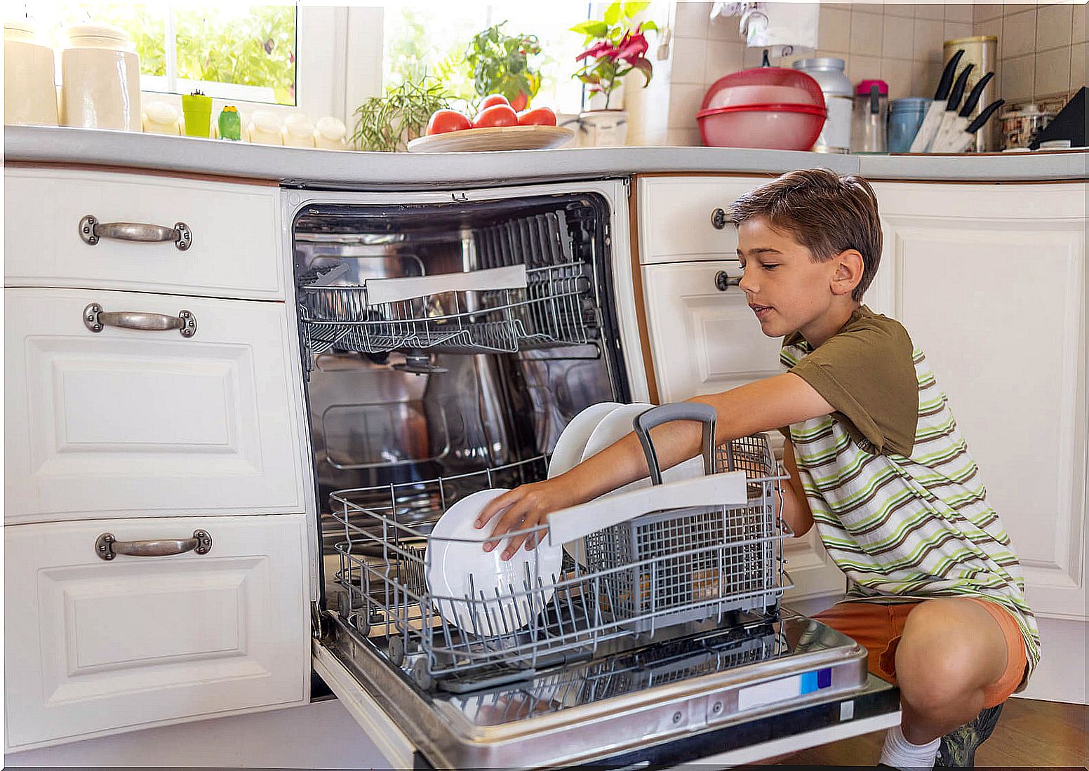 Child putting dirty dishes in the dishwasher.