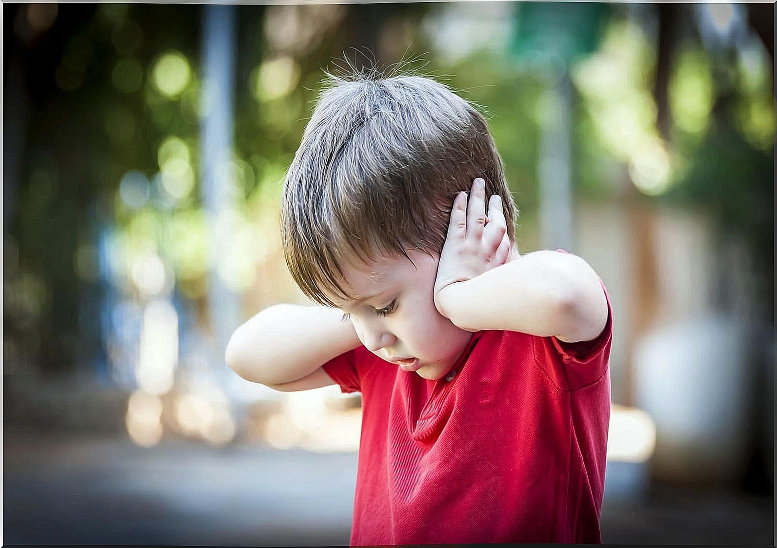 Child with savant syndrome covering his ears.