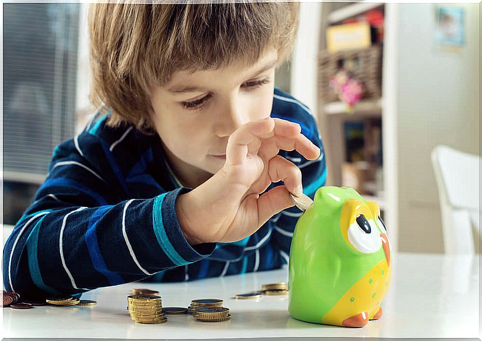 Child putting money in the piggy bank as part of one of the responsibilities that he can assume with his age.