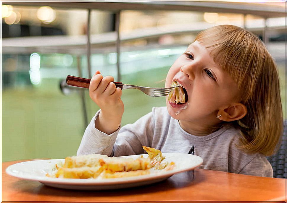 Little girl eating in a restaurant the children's menu.