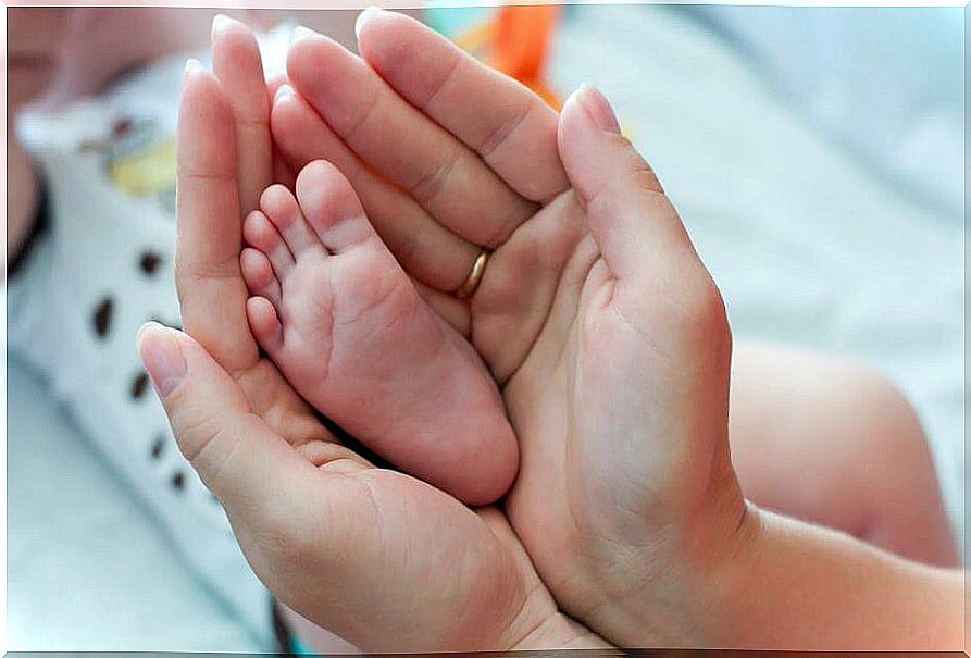 Hands of a mother picking up a baby's foot