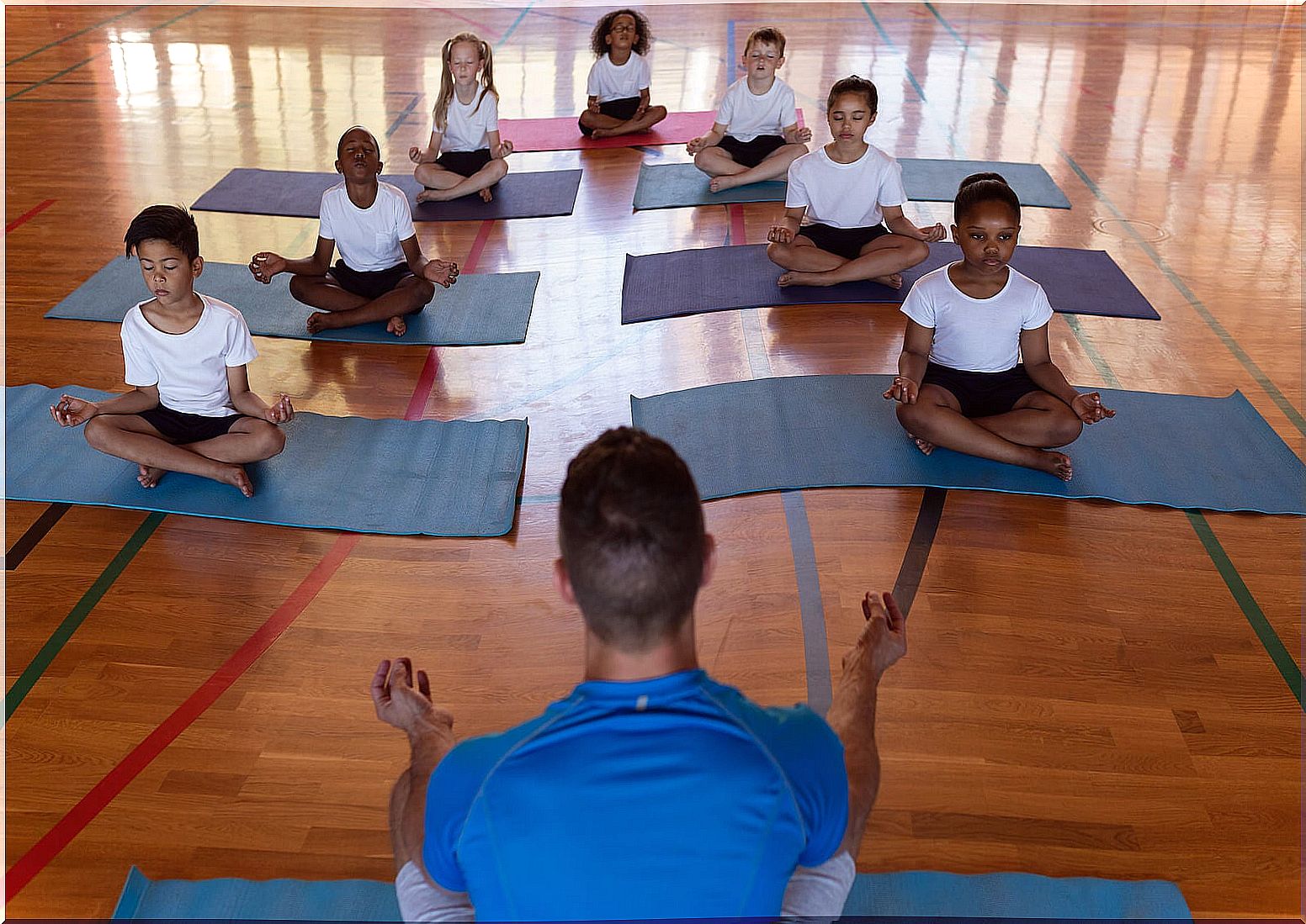 Teacher with his students doing yoga in the classroom.